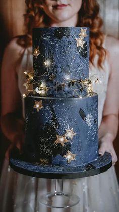 a woman holding a blue cake with stars on it