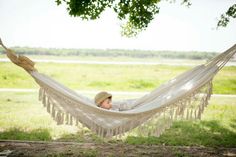 a little boy laying in a hammock on the grass