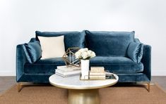 a living room with a blue velvet couch and coffee table