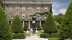 a statue in front of a building surrounded by trees