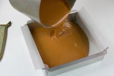 someone pouring caramel sauce into a container