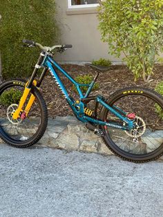 a blue and yellow mountain bike parked in front of a house