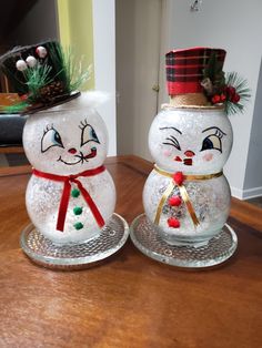 two snowmen sitting on top of a wooden table