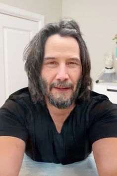 a man with long hair and beard sitting at a table in front of a cake