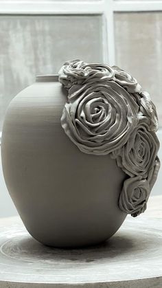 a vase sitting on top of a table next to a window