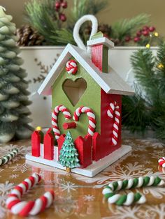 a small house with candy canes around it and christmas decorations on the table behind it