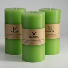 three green candles with labels on them sitting in front of a white background and one candle has a brown label that says mozeal