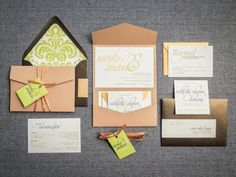 an assortment of wedding stationery and envelopes on a gray surface with yellow tags