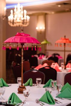 the table is set with pink and green napkins, silverware, and an umbrella