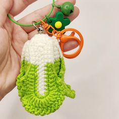 a hand holding a green and white knitted keychain