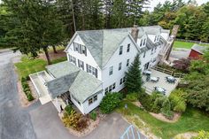 an aerial view of a large white house surrounded by trees