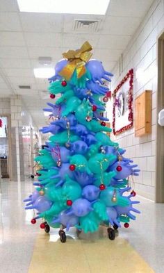 a blue christmas tree in the middle of a hallway with decorations on it's sides