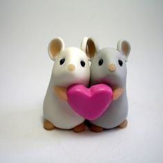 two white mice holding a pink heart shaped object