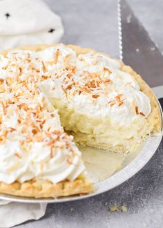 a coconut cream pie on a plate with a slice missing