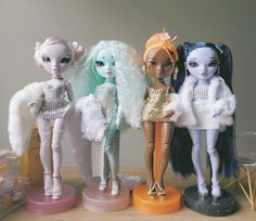 three dolls are standing next to each other in front of a table with toys on it