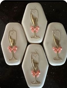 four white coasters with pink bows and champagne glasses on them, sitting on a black surface