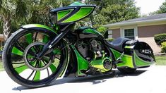 a green and black motorcycle parked in front of a house