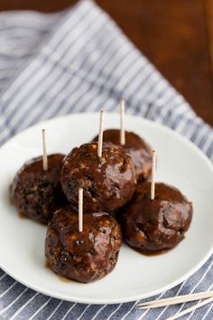 some meatballs are on a white plate with toothpicks