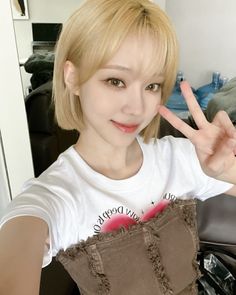 a young woman with blonde hair making the peace sign while sitting in front of a chair