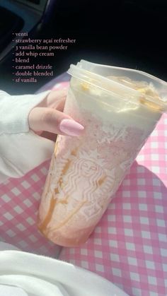 a woman is holding a cup with ice cream in it on a pink and white checkered table cloth