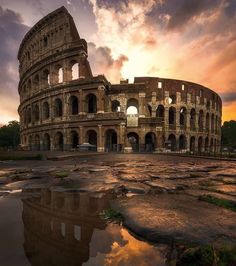 the sun is setting behind an old roman colliseum in rome, italy with water reflecting off the ground