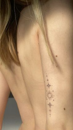 the back of a woman's left shoulder with a small tattoo on her right side