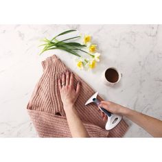 someone is drying their hands on a towel next to some flowers and a coffee mug