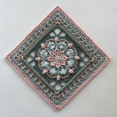 a crocheted square with a flower on the center in pink and blue colors