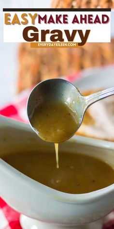 a spoon is pouring gravy into a white bowl with bread in the background