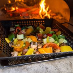 a grill filled with lots of different types of vegetables on it's side and fire in the background