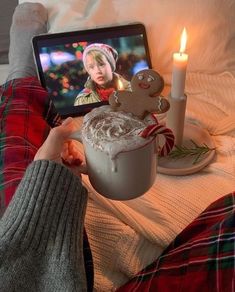 a person holding up a cup with a gingerbread drink in front of a laptop