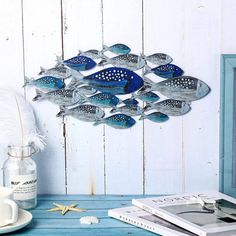 a metal fish sculpture sitting on top of a blue table next to a cup and saucer