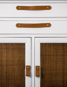 a white cabinet with two brown handles and some wicker on the door handle is shown