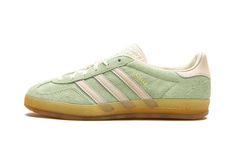 The Women’s adidas Gazelle Indoor “Semi Green Spark” is a women’s-exclusive colorway of the retro indoor soccer shoe with an old school look.  The upper features a Semi Green Spark suede constructed that gives the sneaker a 1970s-era vibe.  Vintage-inspired cream-colored leather Three Stripes branding appears on the sides and a gold “Gazelle” logo can be found on the lateral side of the midfoot.  Additional adidas detailing is seen on the blue textured tongue.  A semi-translucent gum rubber sole completes the look. Adidas Shoes Gazelle, 70s Converse, Adidas Gazelle Indoor, Nike X Travis Scott, Converse Run Star Hike, Adidas Originals Gazelle, Converse Run Star, Sneakers Adidas, Nike Dunk High