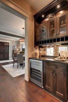 a kitchen with wood flooring and cabinets in the middle of an open living room