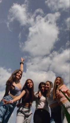 a group of young women standing next to each other under a blue sky with clouds