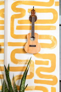 a guitar hanging on the wall next to a plant