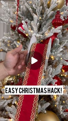 a person holding a knife next to a christmas tree with red and gold ribbons on it