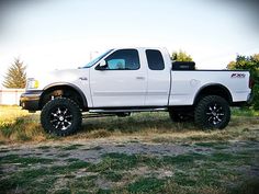 a white truck parked on top of a grass covered field