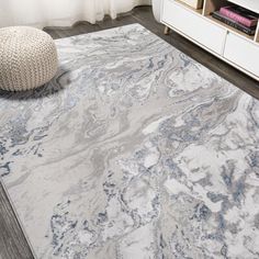 a white rug with blue and gray marble design on it in a living room area