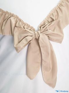 the back of a woman's tan top with a large bow tie on it