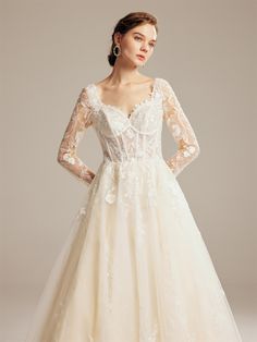 a woman wearing a wedding dress with long sleeves and a lace overlay on it