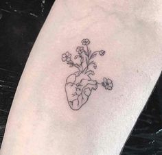 a small heart tattoo with flowers on the arm