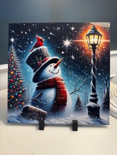 a painting of a snowman with a red hat and scarf next to a lamp post