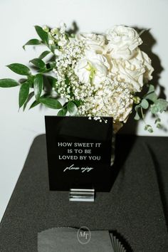 a bouquet of white flowers sitting on top of a table next to a card that says, how sweet it is to be loved by you