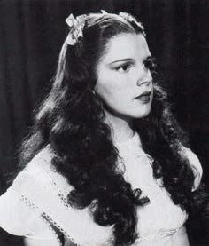 an old black and white photo of a woman with long hair wearing a headband