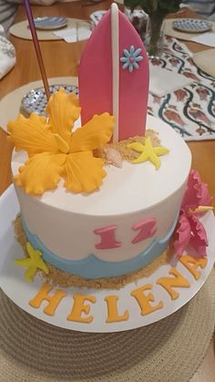 there is a cake that has been decorated with flowers and surfboards on the top