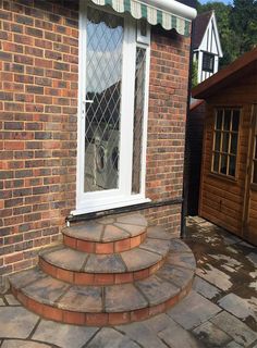 a dog is sitting in the window of a brick house with steps leading up to it