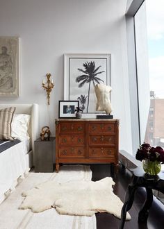 a bed room with a neatly made bed next to a window and a wooden dresser