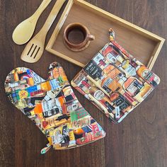 two oven mitts and spoons are sitting on a wooden table next to a tray with utensils